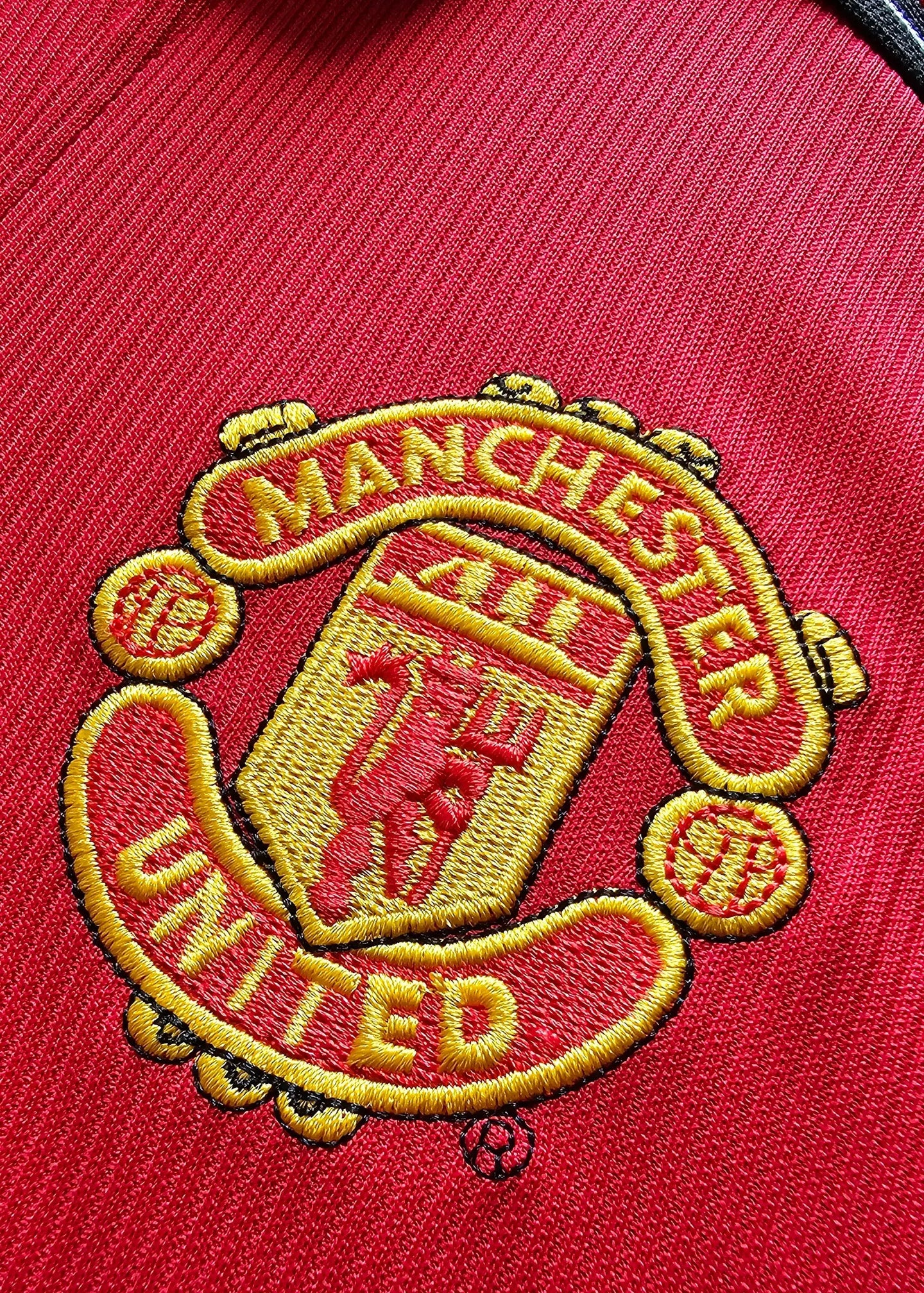 Close-up of the embroidered Manchester United crest with the text 'MANCHESTER' and 'UNITED'.