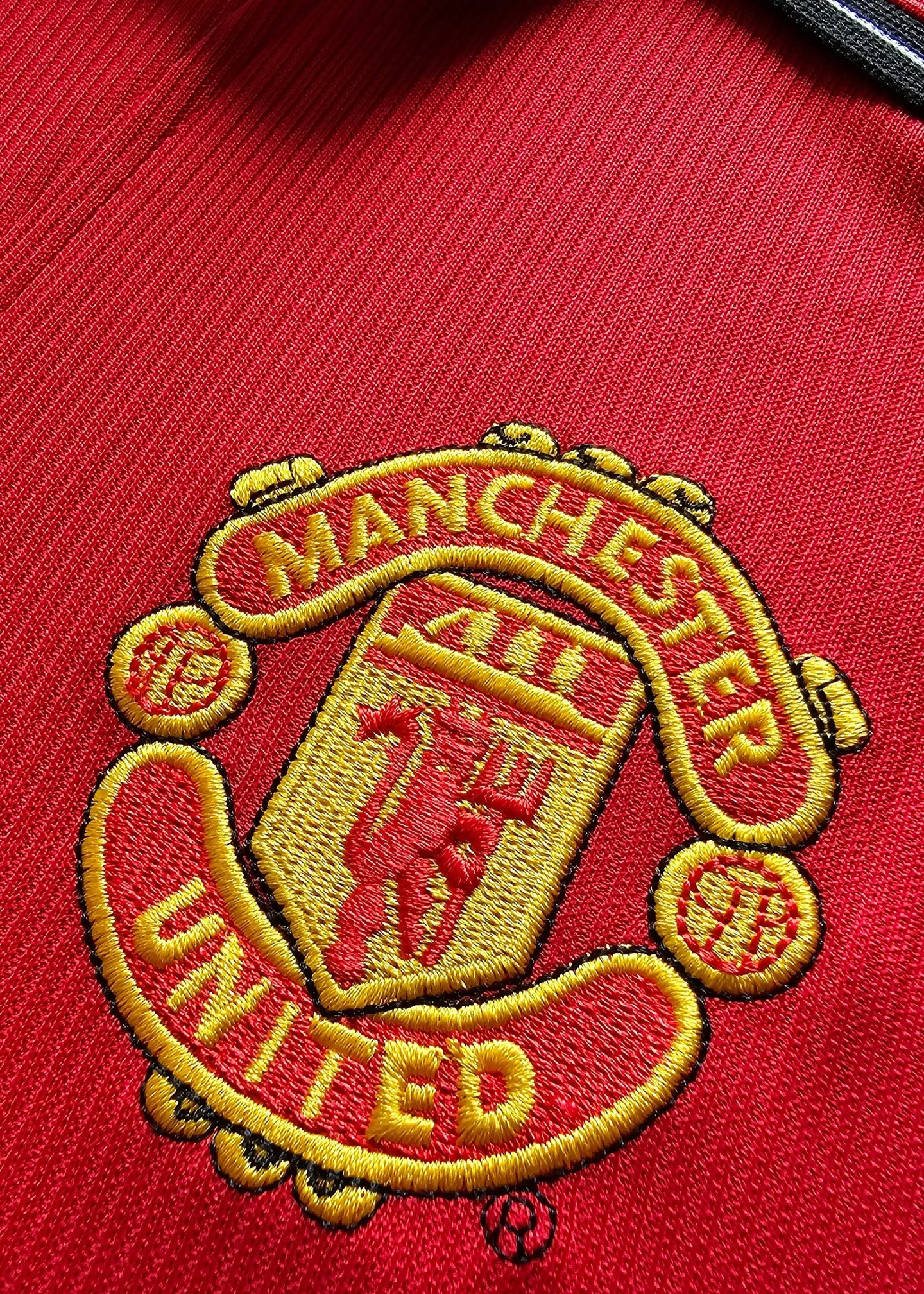 Close-up of the Manchester United crest featuring red and yellow embroidery.