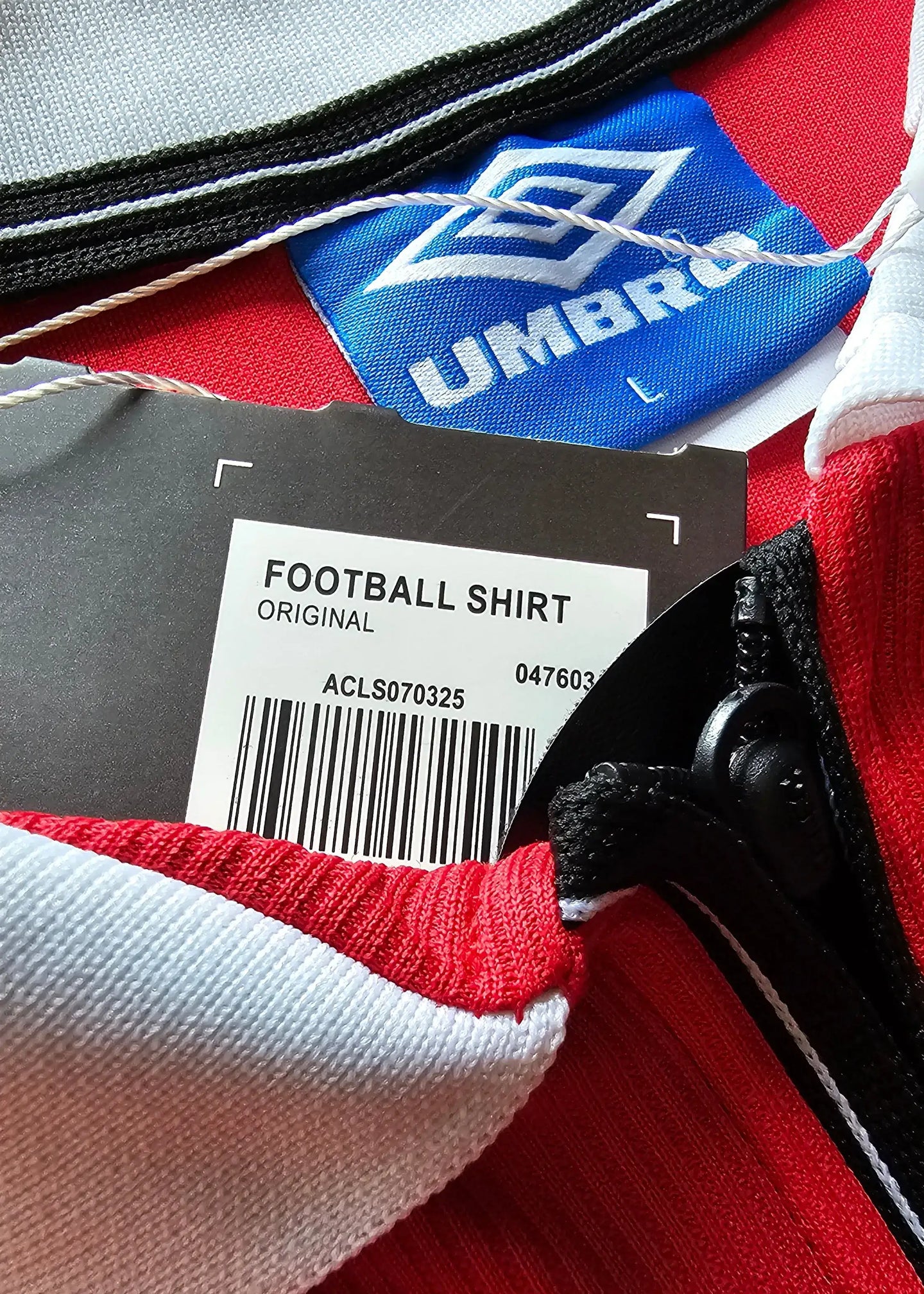Crest detail showing Umbro tag and care label reading 'FOOTBALL SHIRT ORIGINAL'.