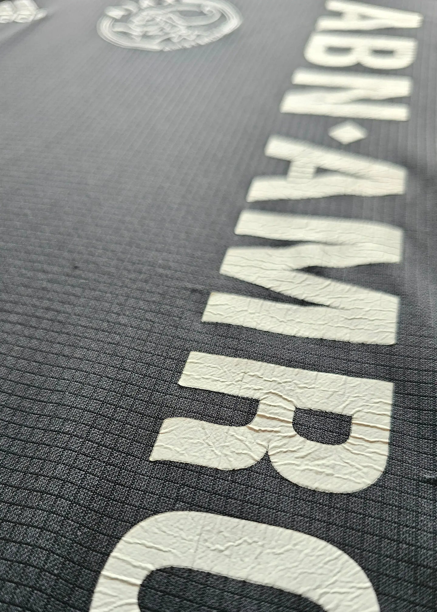 Detail showing the white ABN AMRO sponsor text and Ajax crest on the black shirt.