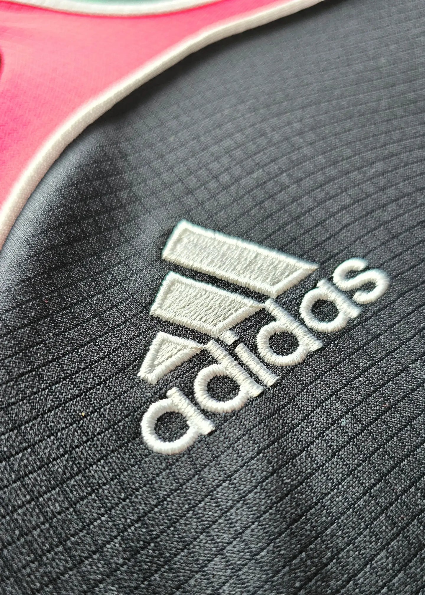 Close-up of the Adidas logo on the shirt, showcasing the embroidered detail.