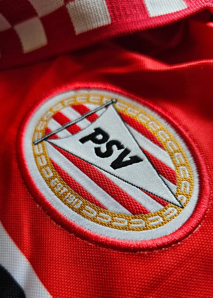 Close-up of the PSV Eindhoven crest featuring red and white stripes with the word &