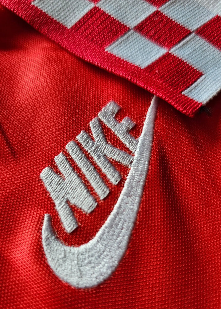 Close-up of Nike logo and red fabric featuring checkered pattern.