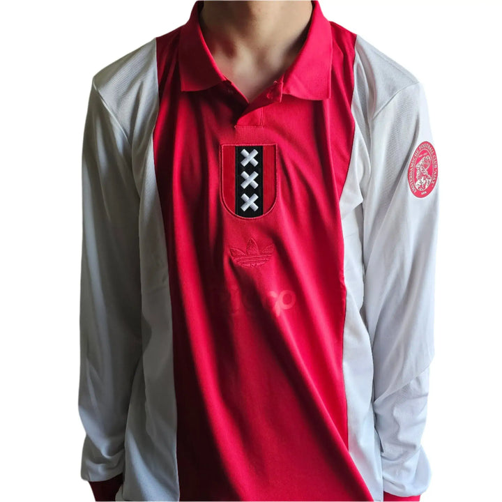 Front view of the red and white football shirt with Ajax crest and three X's detail.