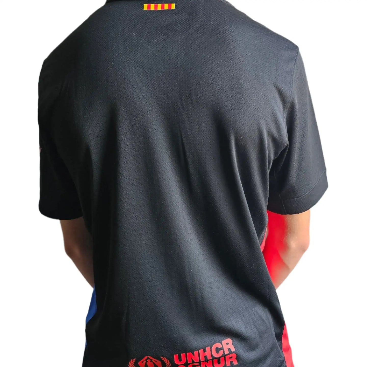 Back view showing the black FC Barcelona 2025 shirt with red UNHCR logo and yellow detailing.