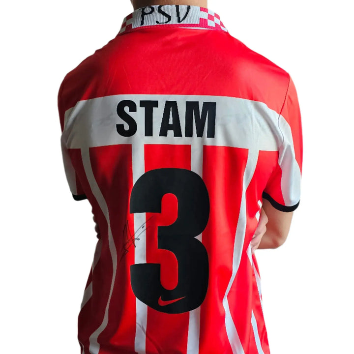 Back view showing Stam, No. 3, with signature on a red and white striped football shirt.