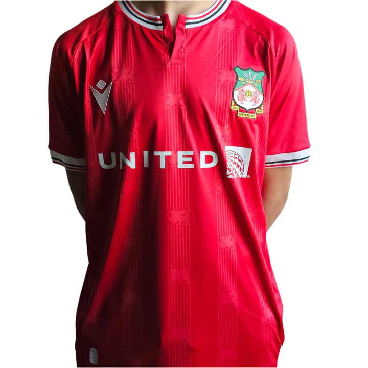 Front view of Wrexham AFC soccer jersey in red with crest and UNITE logo visible.