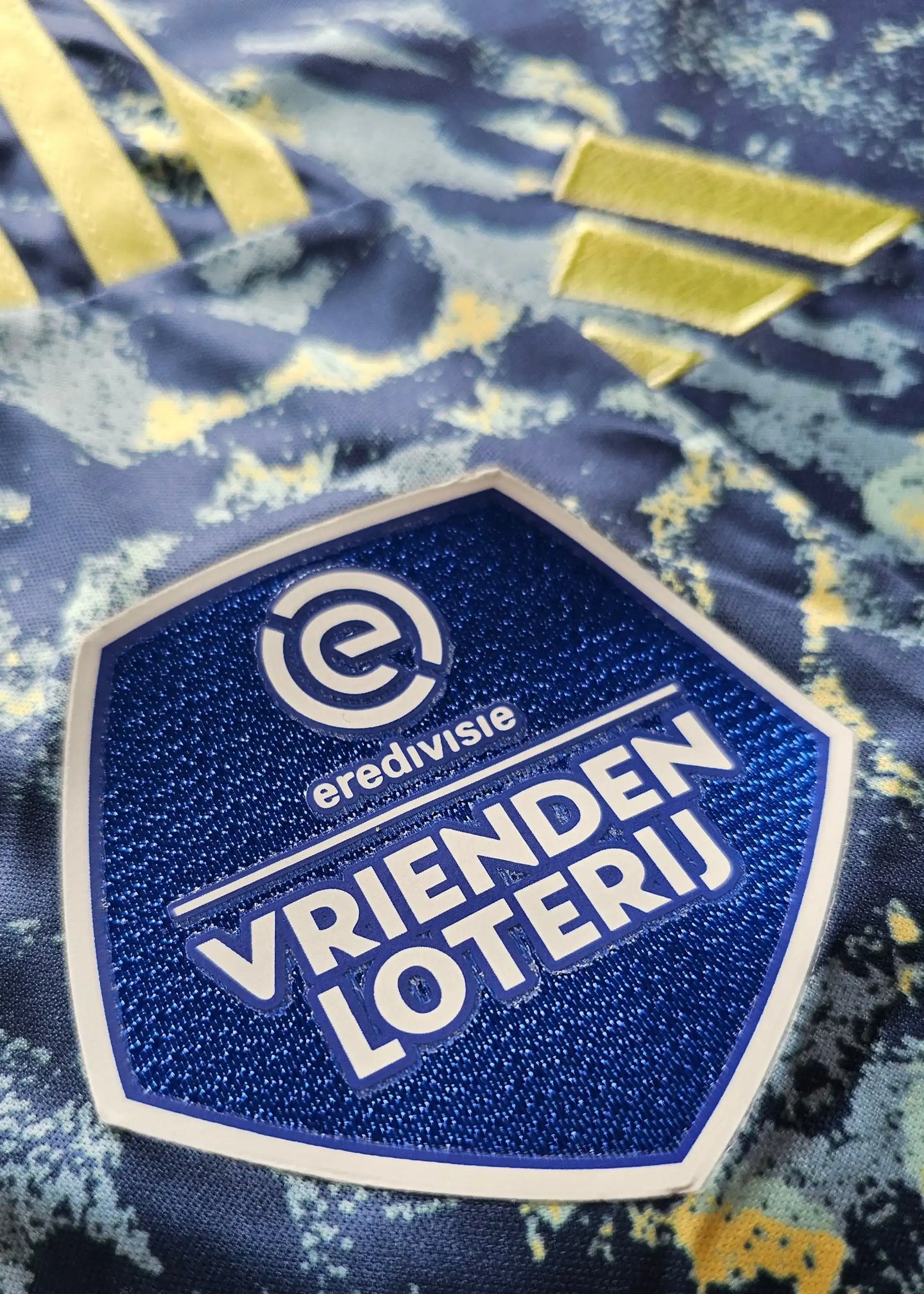 Detailed view showing the Vrienden Loterij logo and erdivisie text on the blue and yellow shirt.