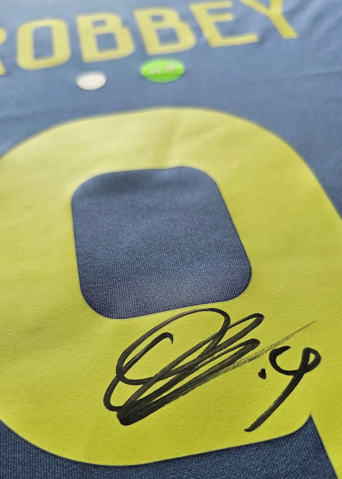 Close-up showing the signature of Brobbey and No. 9 in yellow on the blue football shirt.