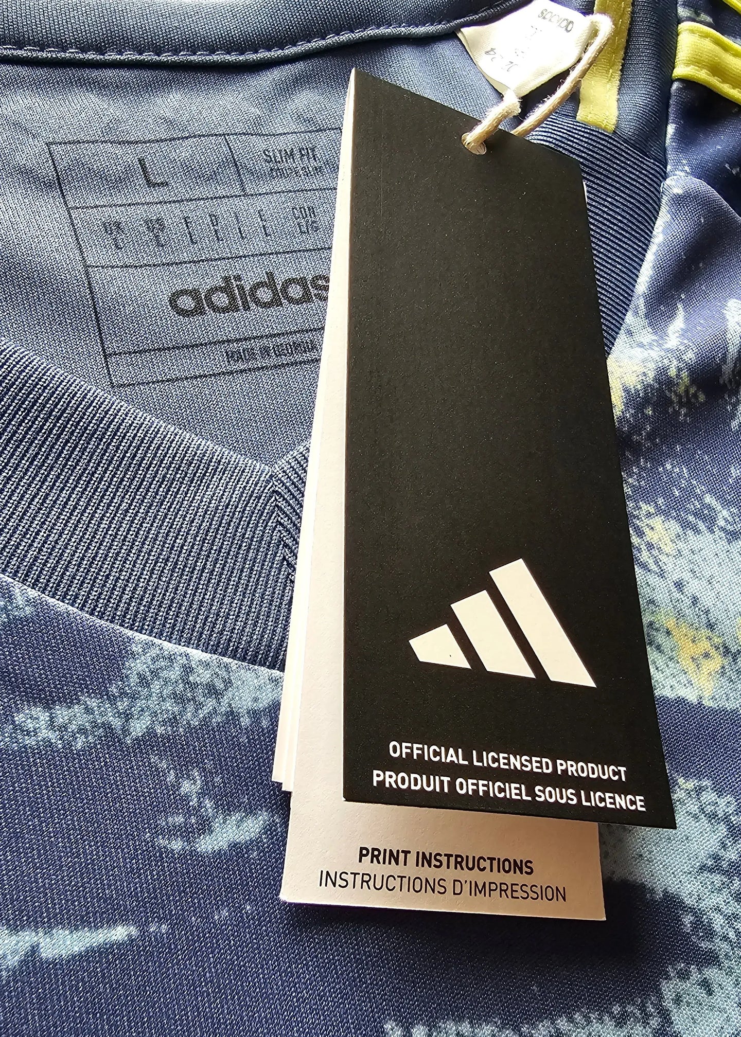 Label showing size L and adidas branding on a blue football shirt with yellow accents.