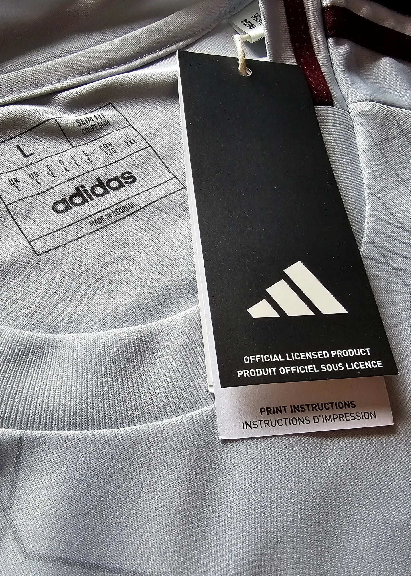 Size L tag with adidas logo and care instructions, showing grey fabric details.