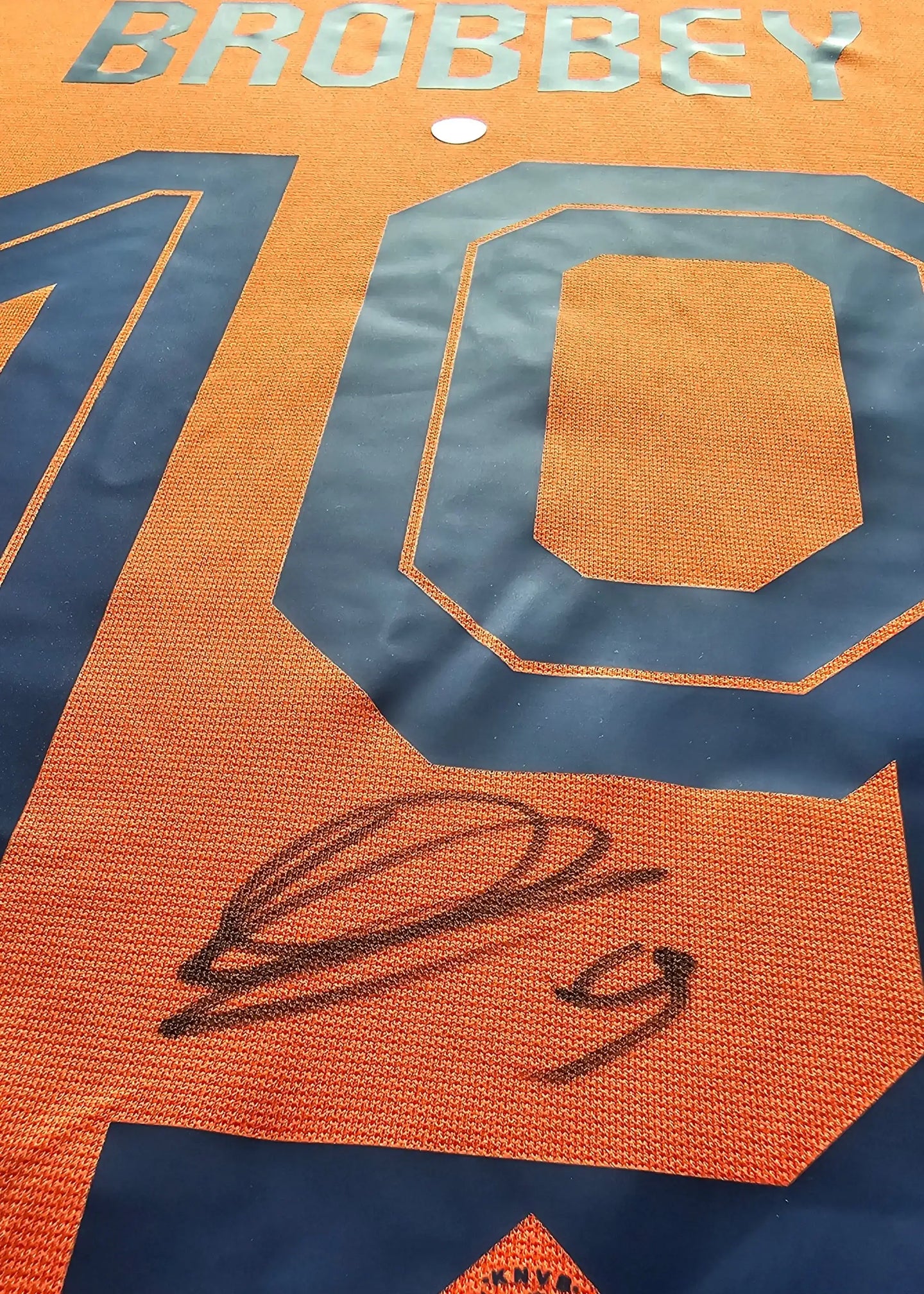 Detail showing signature and the name Brobbey above No. 10 on orange football shirt.