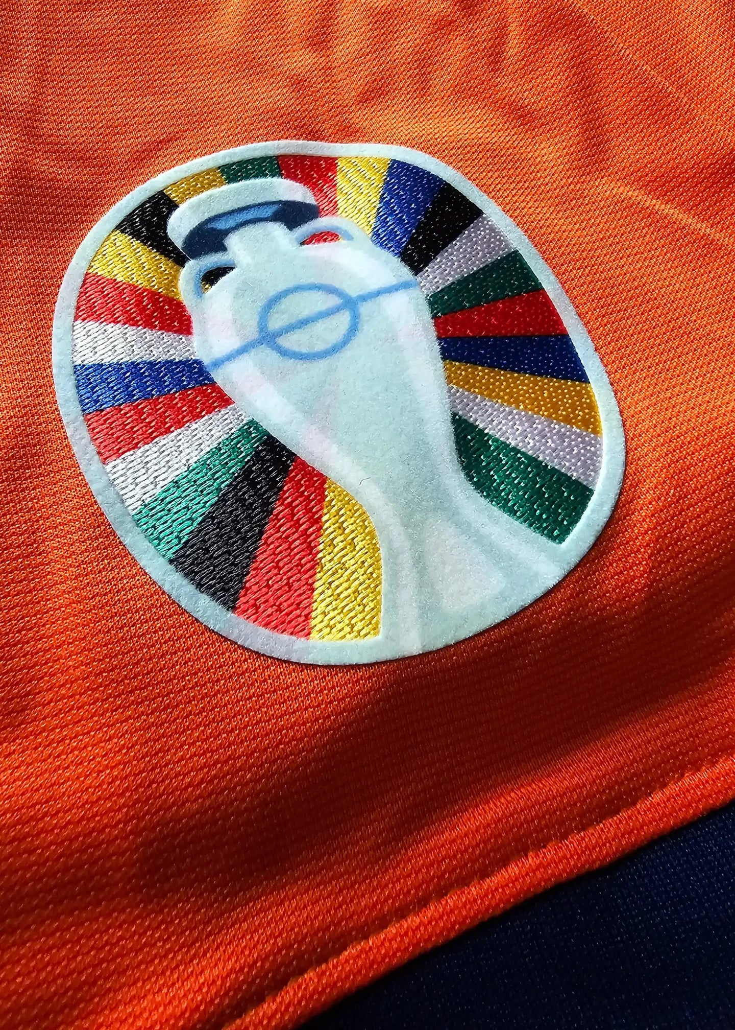 Close-up of Euro 2024 crest detail featuring colorful design on an orange background.