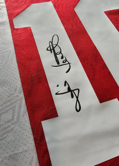 Detail view showing No. 10 and signature on a red Ajax football shirt.