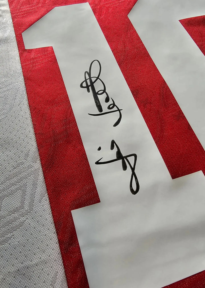 Detail view showing No. 10 and signature on a red Ajax football shirt.