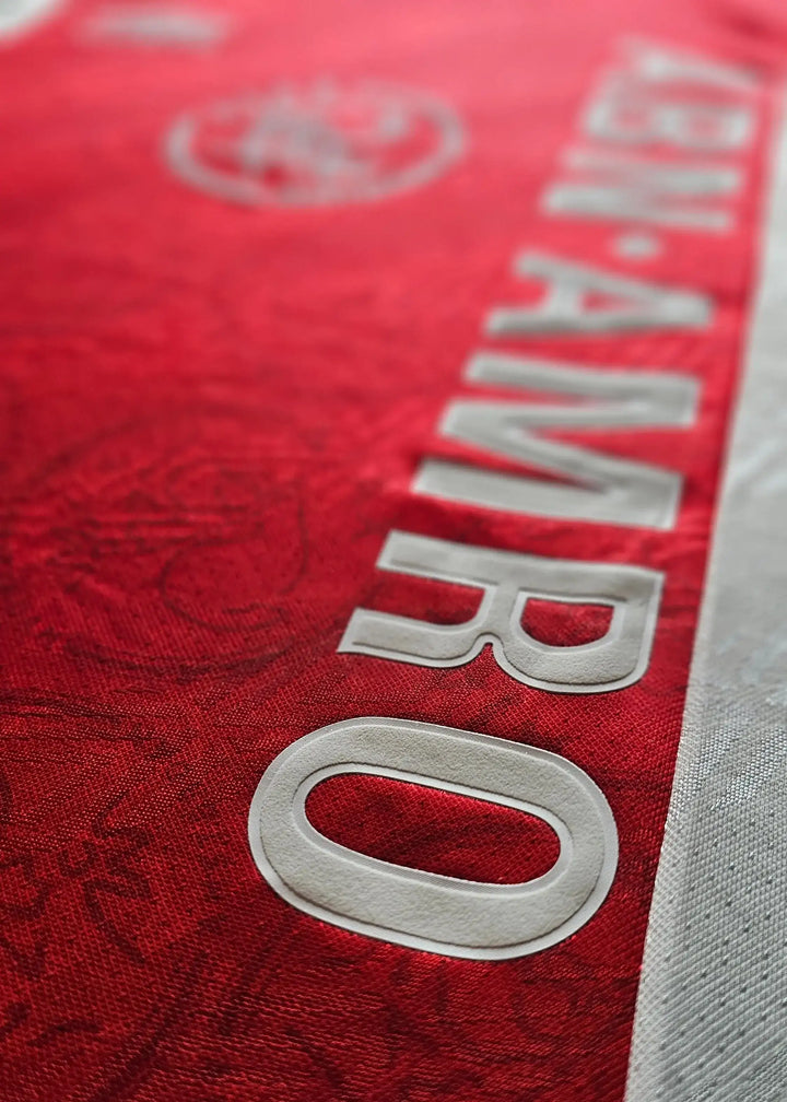 Detail showing the white 'ABN AMRO' wordmark on the red 1994-95 Ajax football shirt.