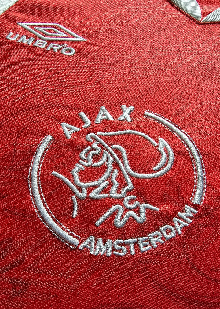 Embroidered AJAX crest with AMSTERDAM on red background and Umbro logo above.