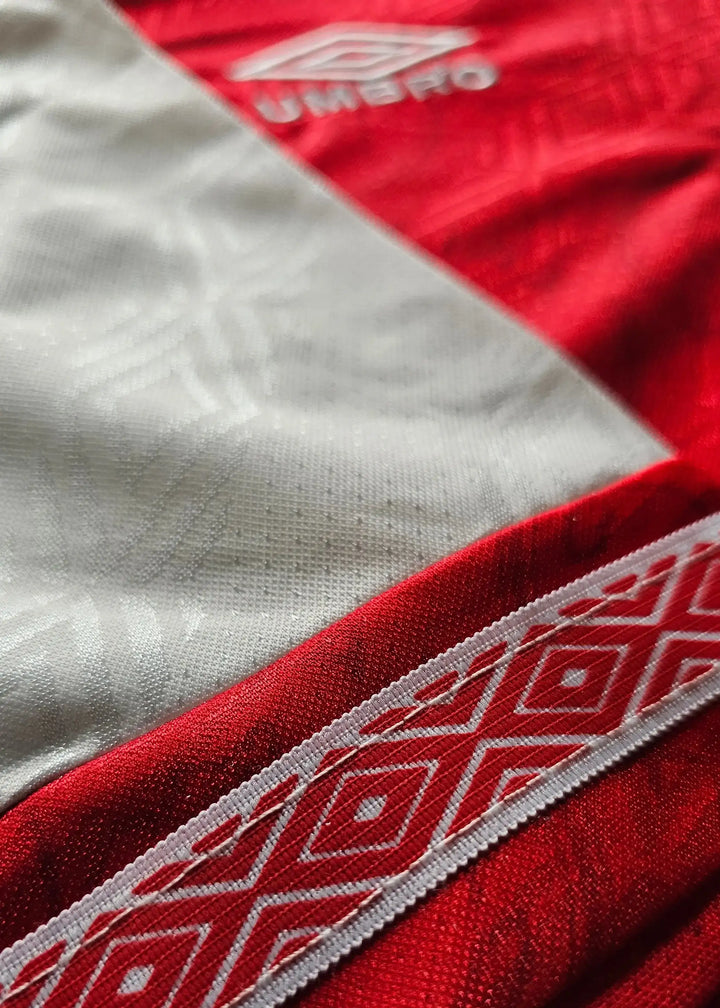 Detail view showing red and white sections with Umbro logo on a signed football shirt.