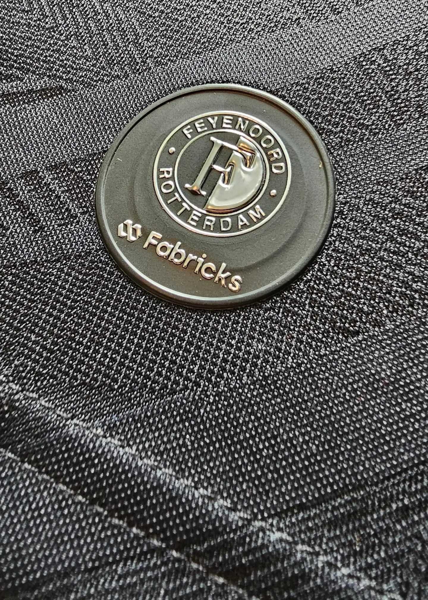 Crest detail featuring Feyenoord Rotterdam logo and Fabricks brand on a black fabric.