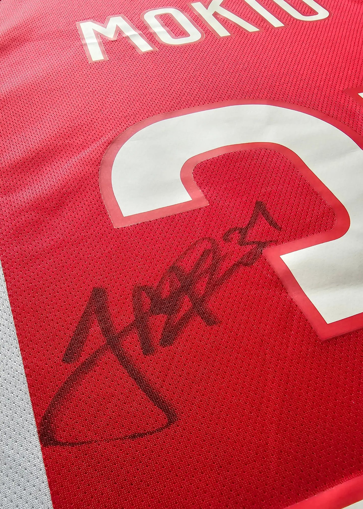 Detail showing Jorthy Mokio's signature on the back of the red Ajax football shirt with No. 31.