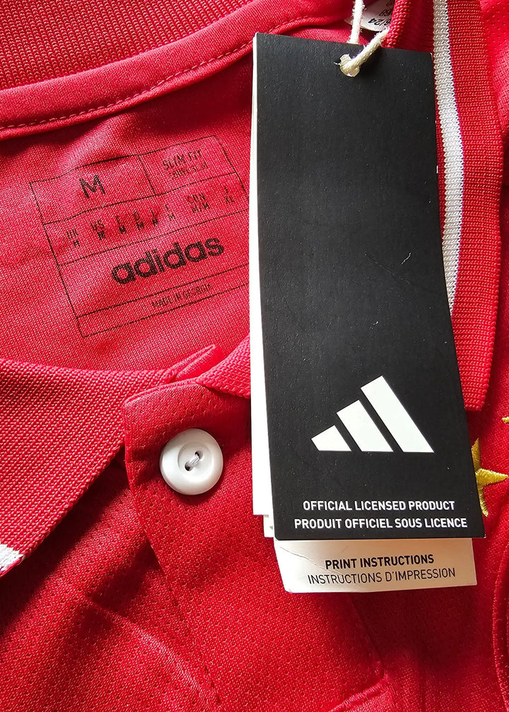 Close-up of the adidas tag and size label on a red Ajax football shirt with white accents.