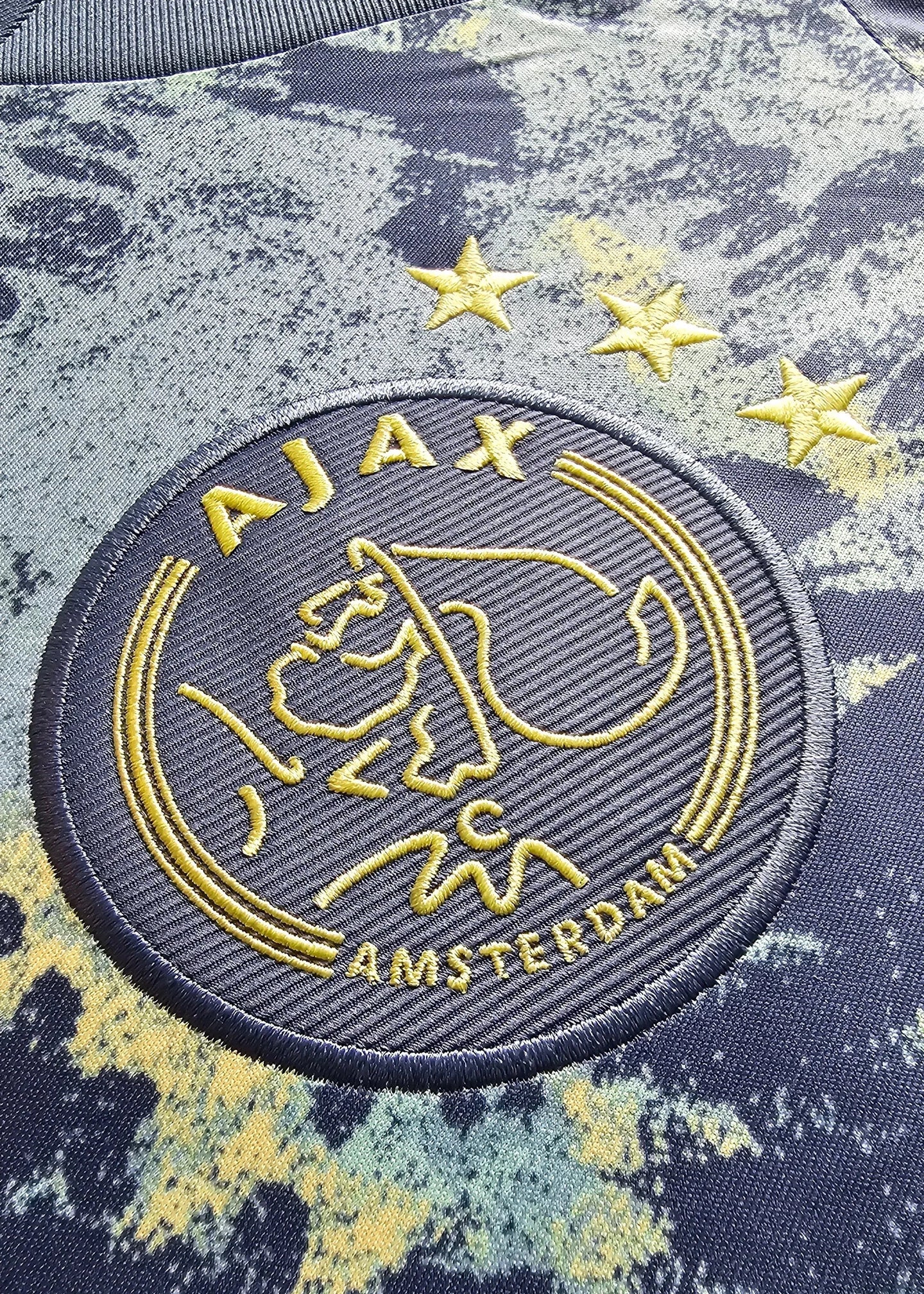 Crest detail with Ajax logo featuring three stars and "AJAX AMSTERDAM" text.