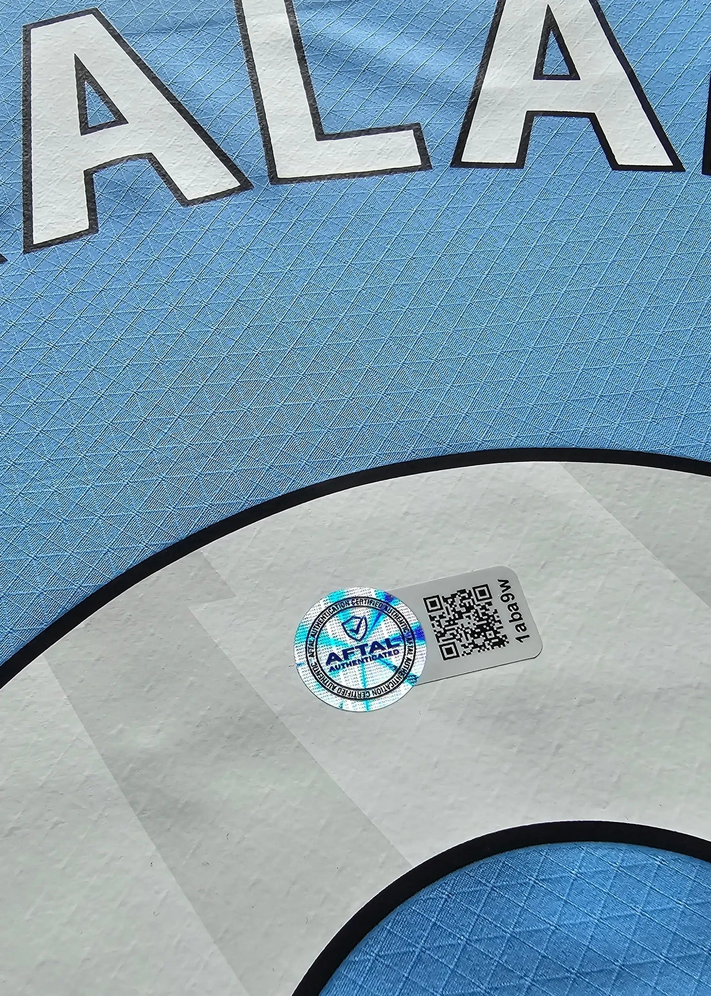 Close-up view of the AFTALS authentication sticker on Erling Haaland's signed football shirt.