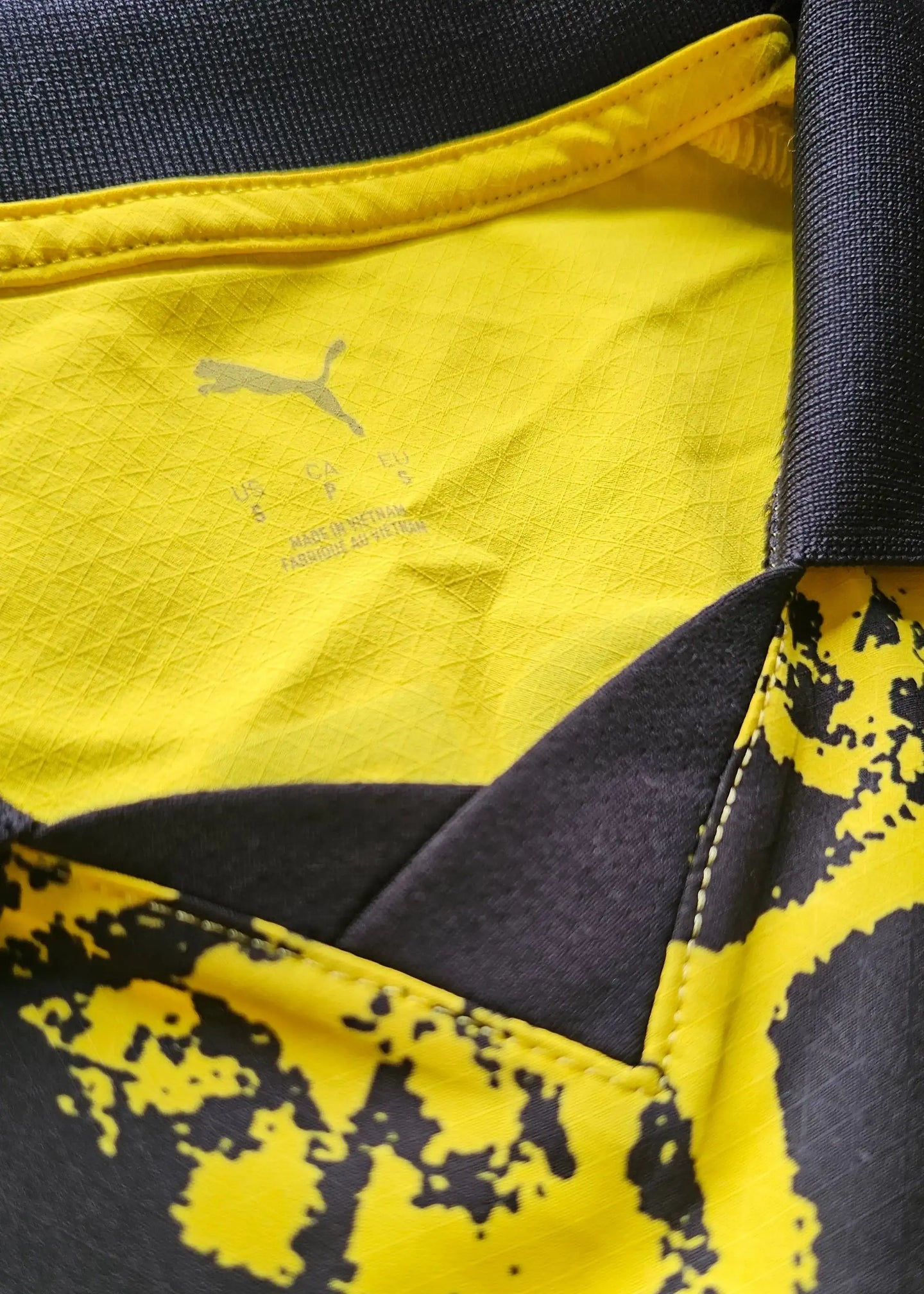 Detail view of the inside collar showing Puma logo and care label on yellow fabric.