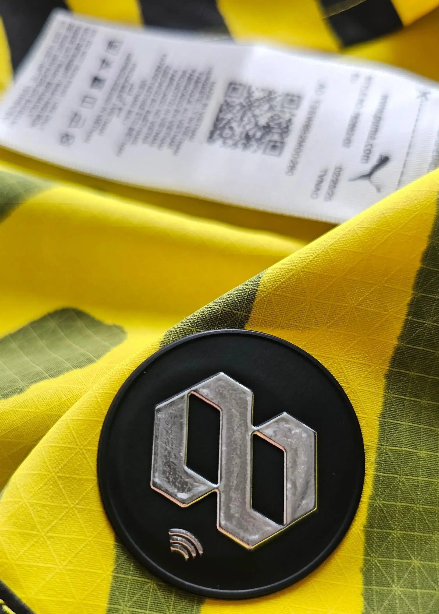 Close-up of Borussia Dortmund crest on a yellow fabric with care label visible.