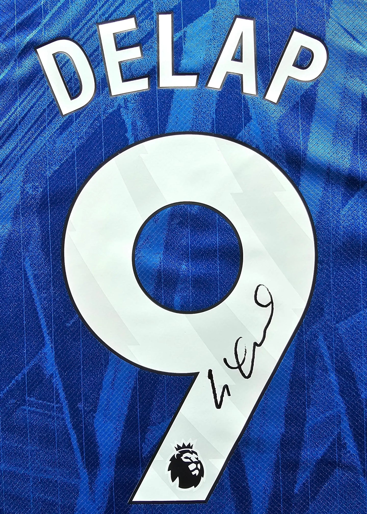 Back view showing the name DELAP, No. 9, and a visible signature on a blue football shirt.