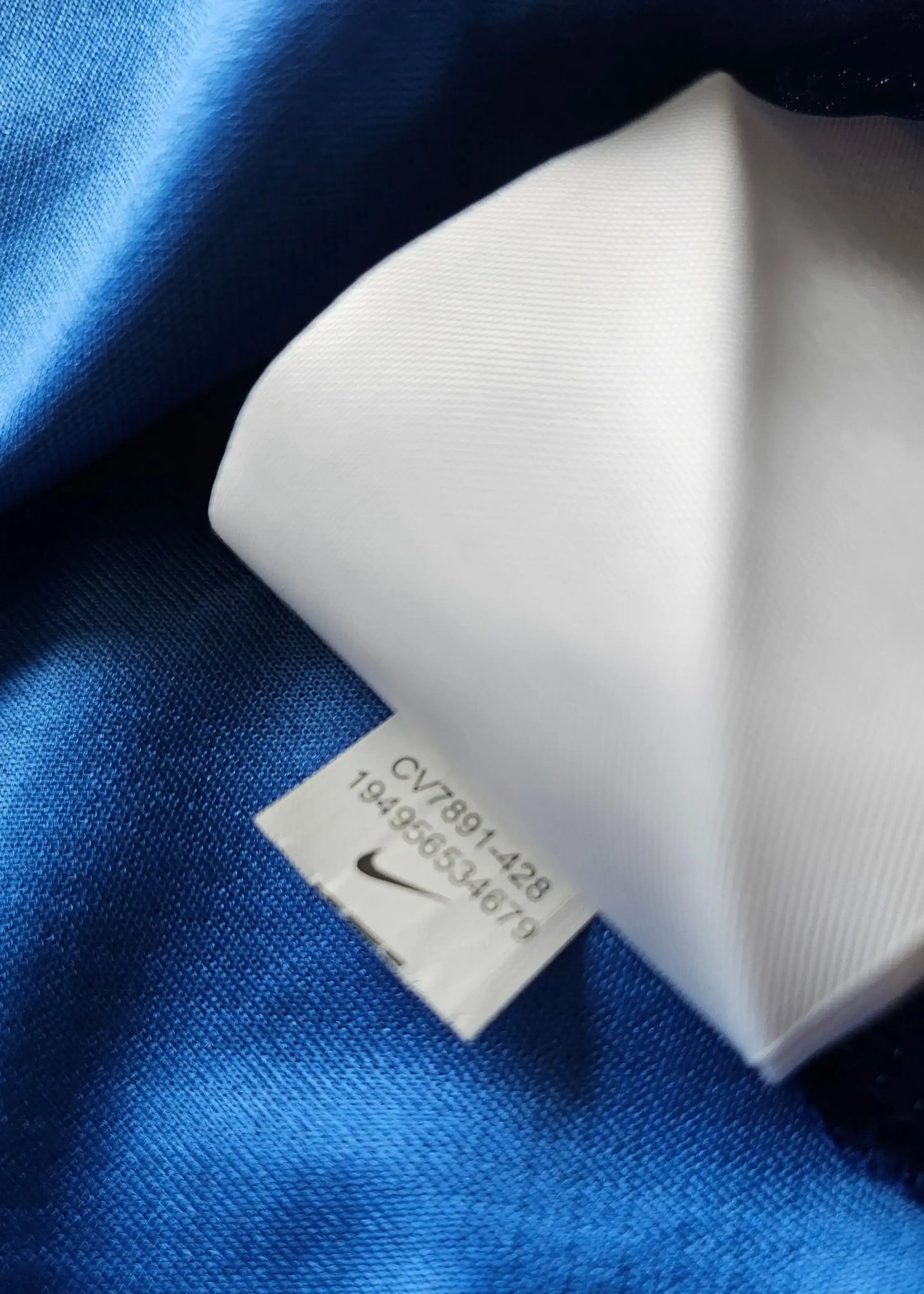 Size label showing Nike logo and care instructions on blue fabric.