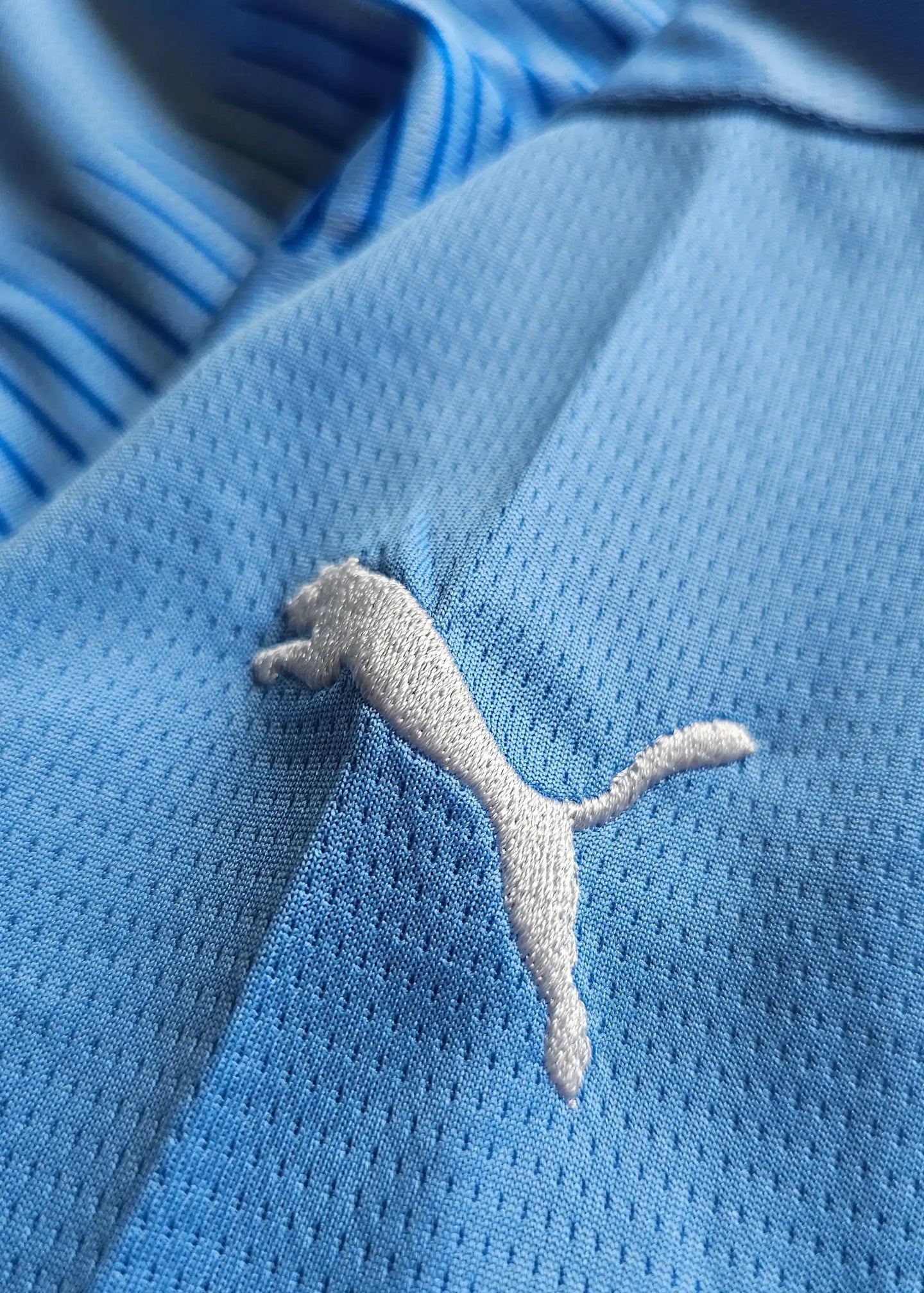 Close-up of the Puma logo on the blue Manchester City 2023-2024 football shirt.