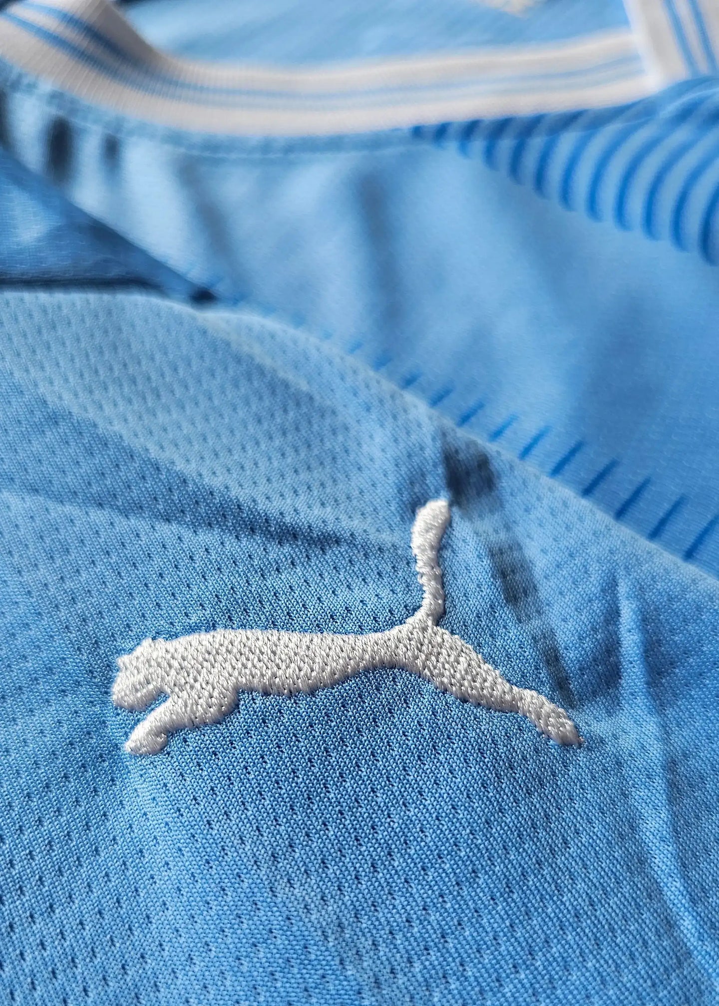 Close-up of Puma logo on blue football shirt.