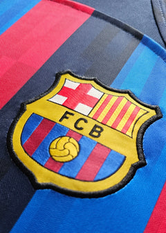 Close-up of the FC Barcelona crest featuring red and blue stripes and the embroidered FCB logo.