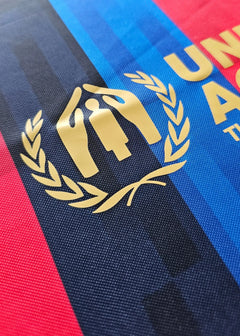 Detail of the FC Barcelona crest featuring gold emblem and laurel leaves.