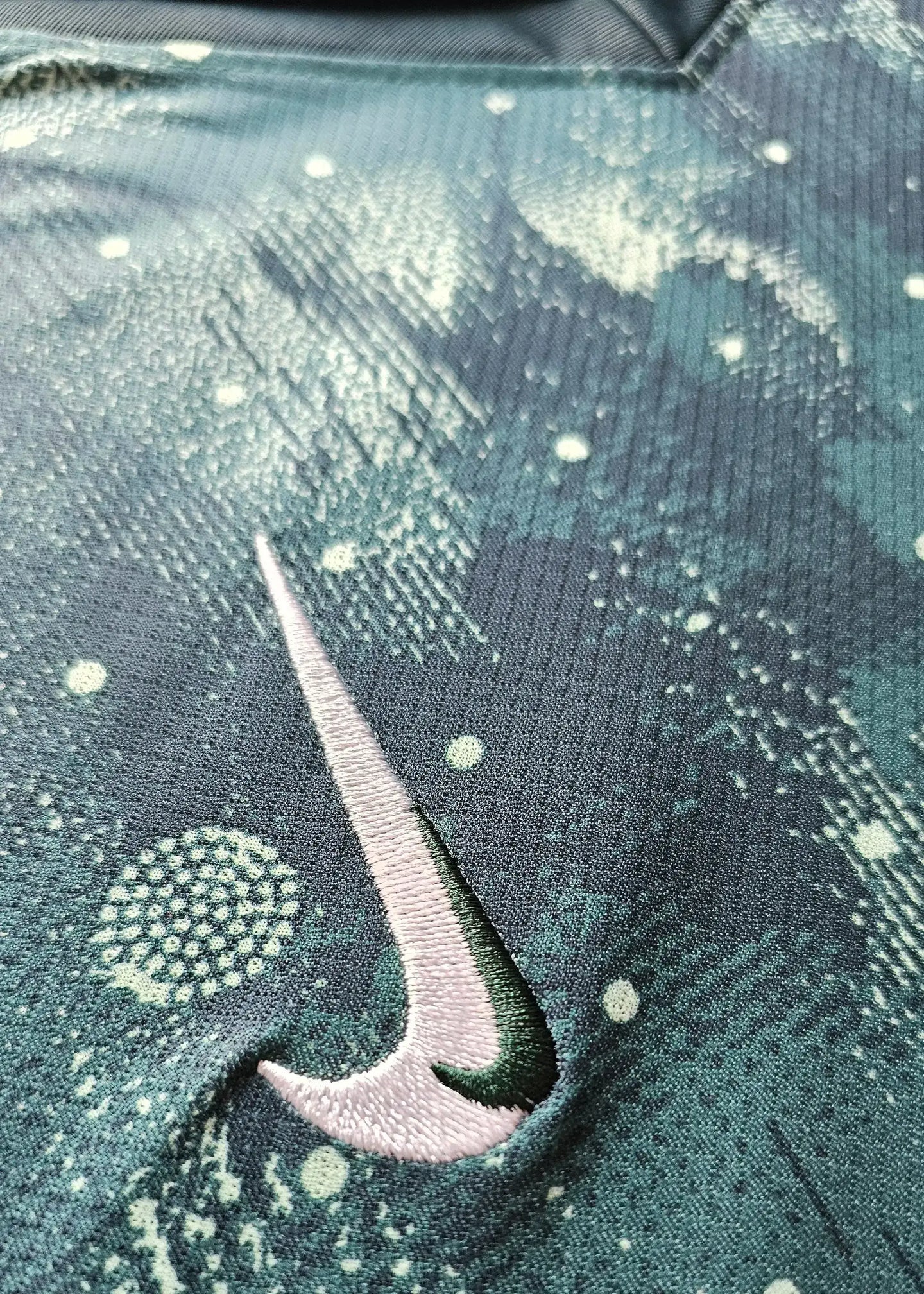 Close-up of Nike logo on blue and green fabric with textured pattern.