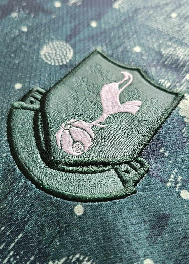 Close-up of the Tottenham Hotspur crest featuring a cockerel atop a football with motto underneath.