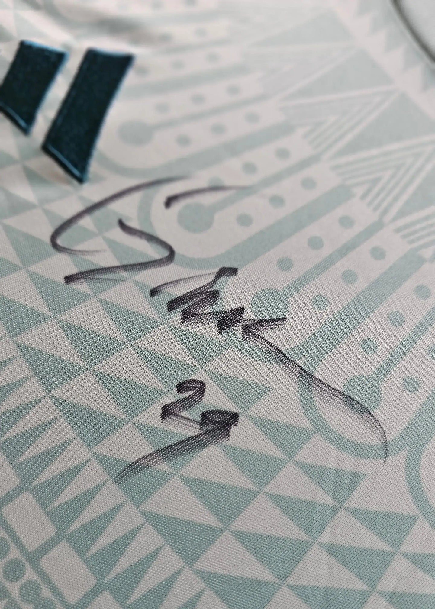 Close-up of Santiago Giménez's signature on the away football shirt featuring geometric patterns.