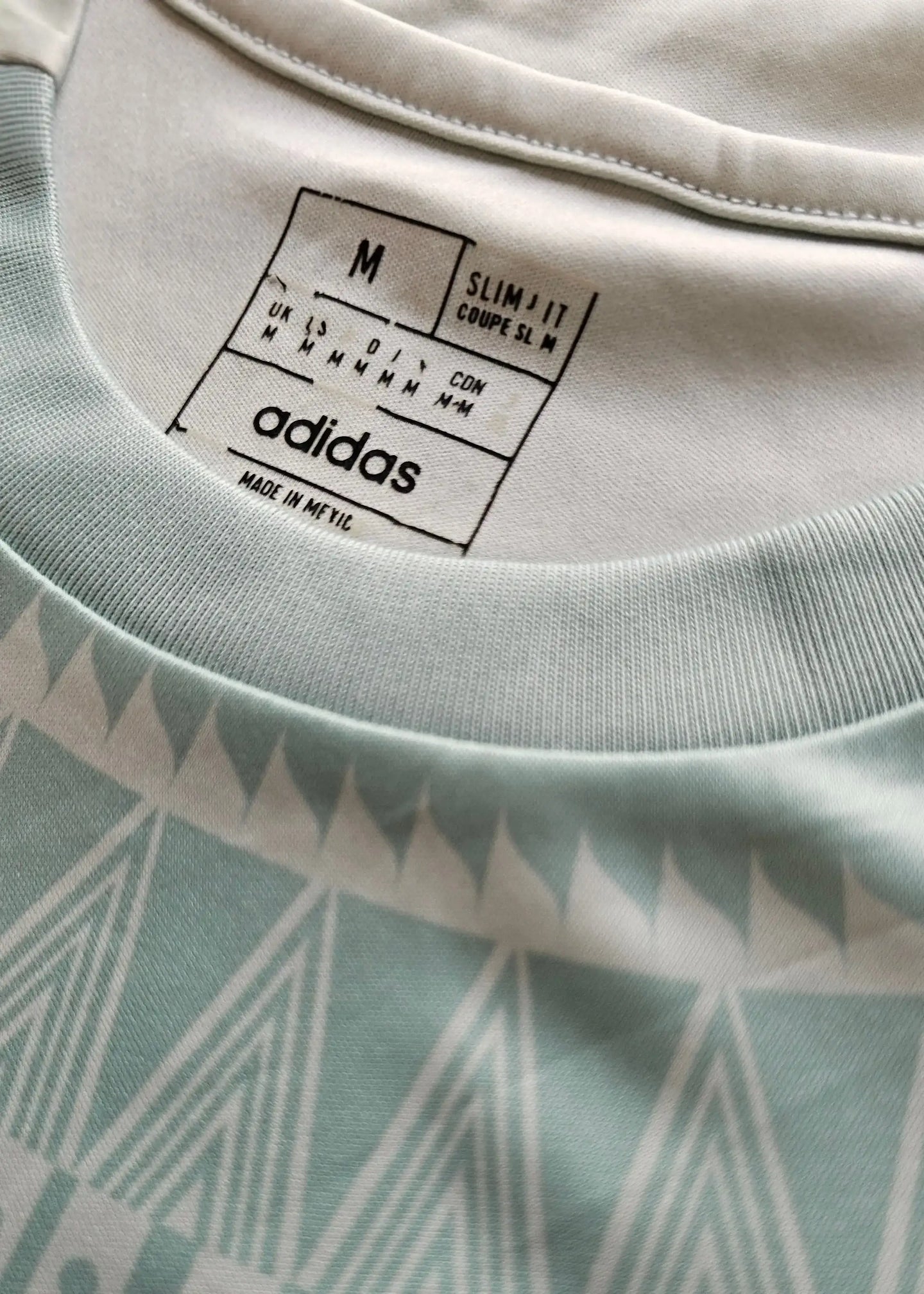 Size label showing M, slim fit, and adidas brand. Care instructions and origin details visible.