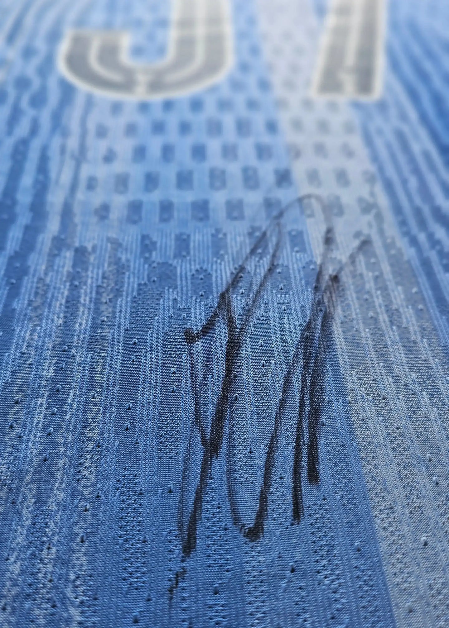 Close-up showing signature on blue football shirt with No. 37.
