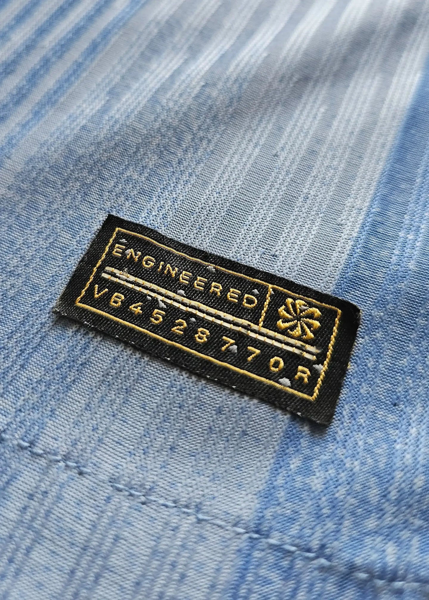 Close-up of the ENGINEERED label on a blue football shirt with code V84528770R.