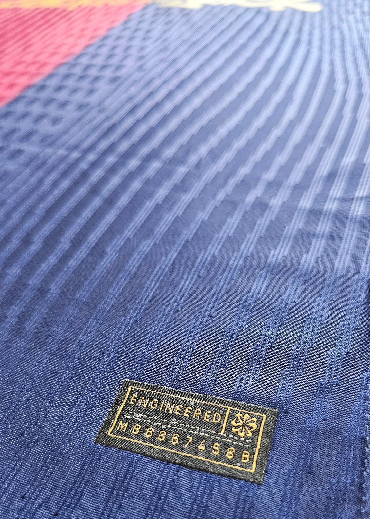 Close-up of the 'ENGINEERED' label on Pau Cubarsi signed Barcelona football shirt with design details.