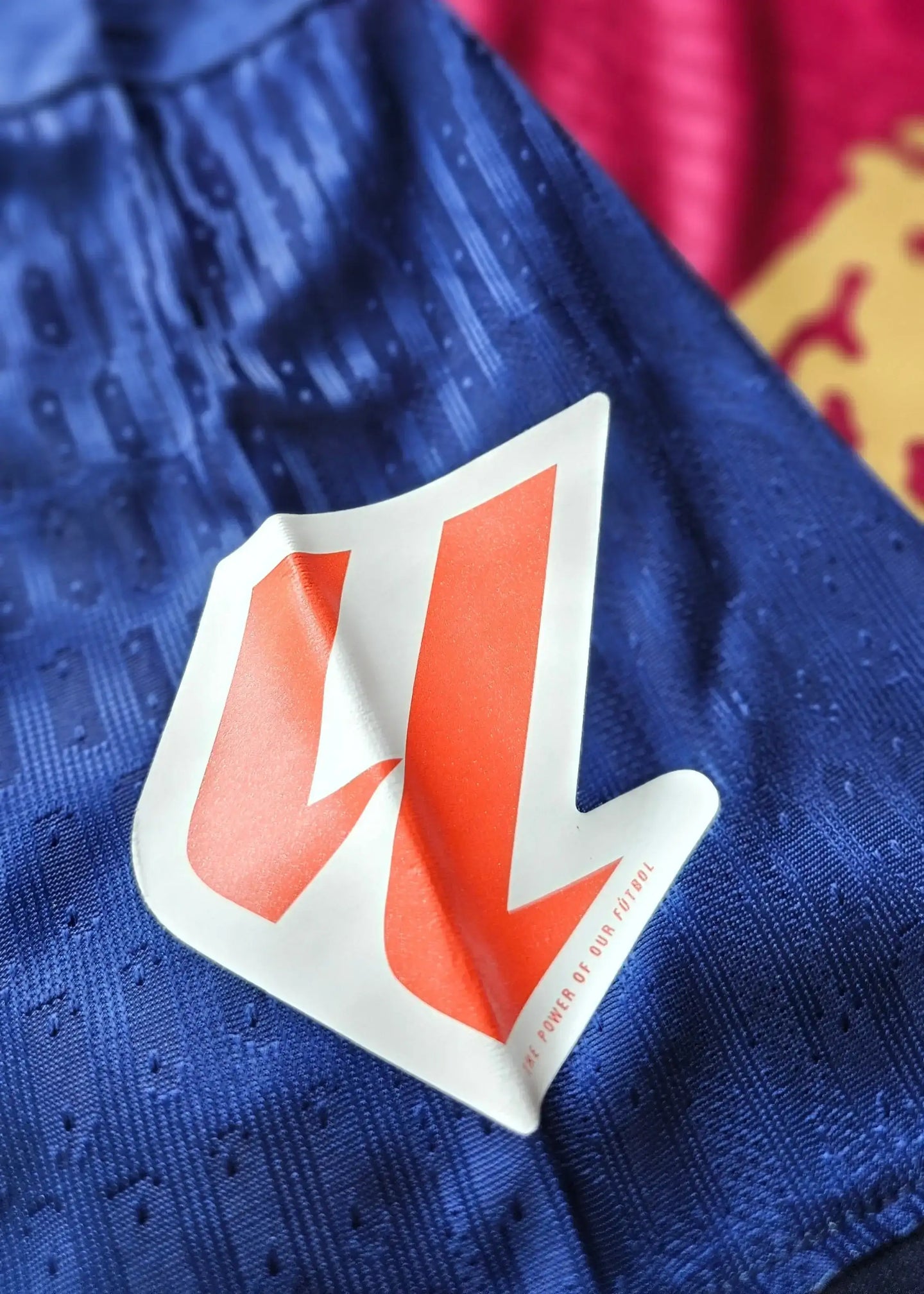 Detail view showcasing the orange and white logo on a blue Barcelona football shirt.