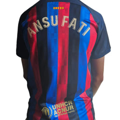 Back view showing ANSU FATI and UNHCR sponsor logo on a blue and red football shirt.