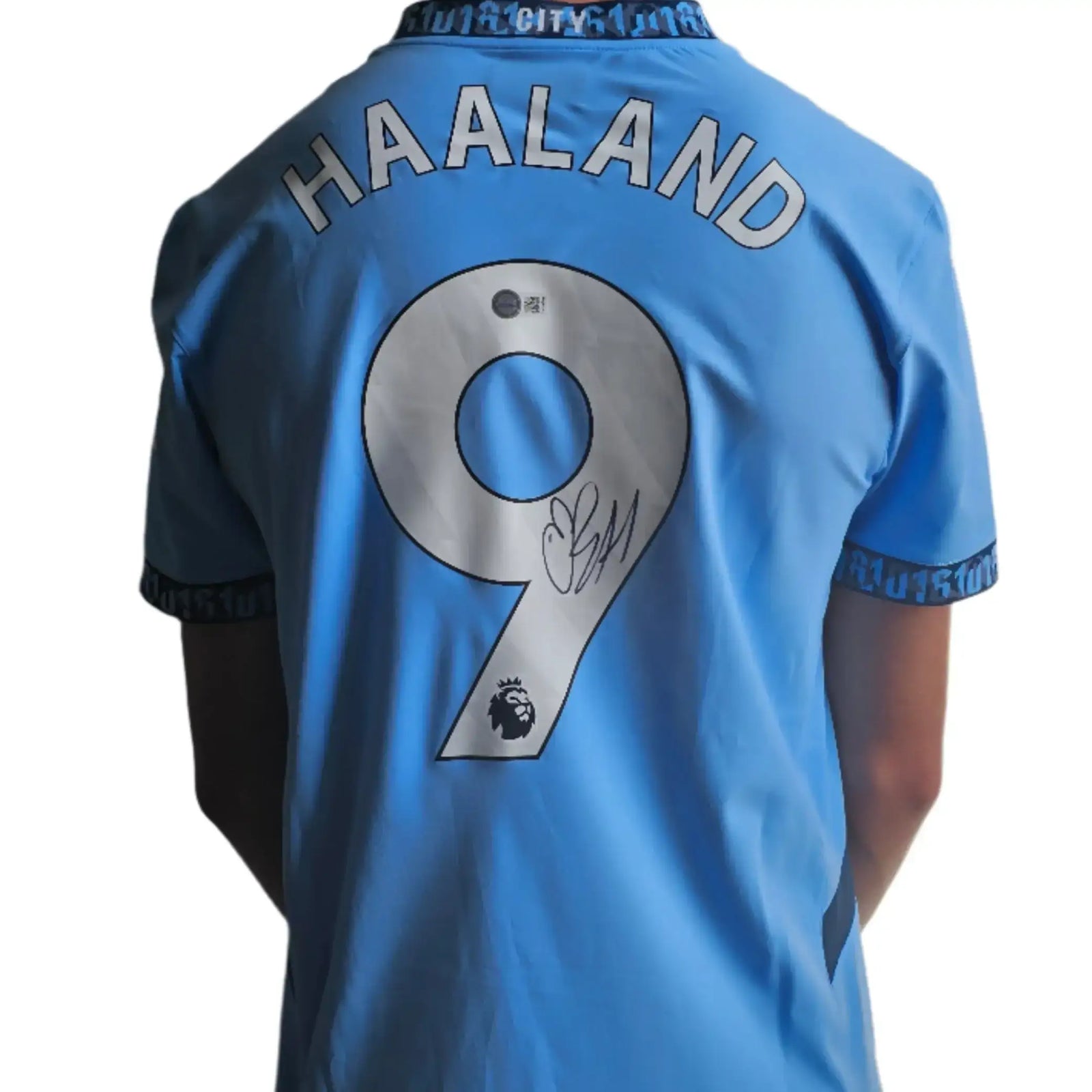 Back view showing Haaland, No. 9, and a visible signature on the Manchester City football shirt.