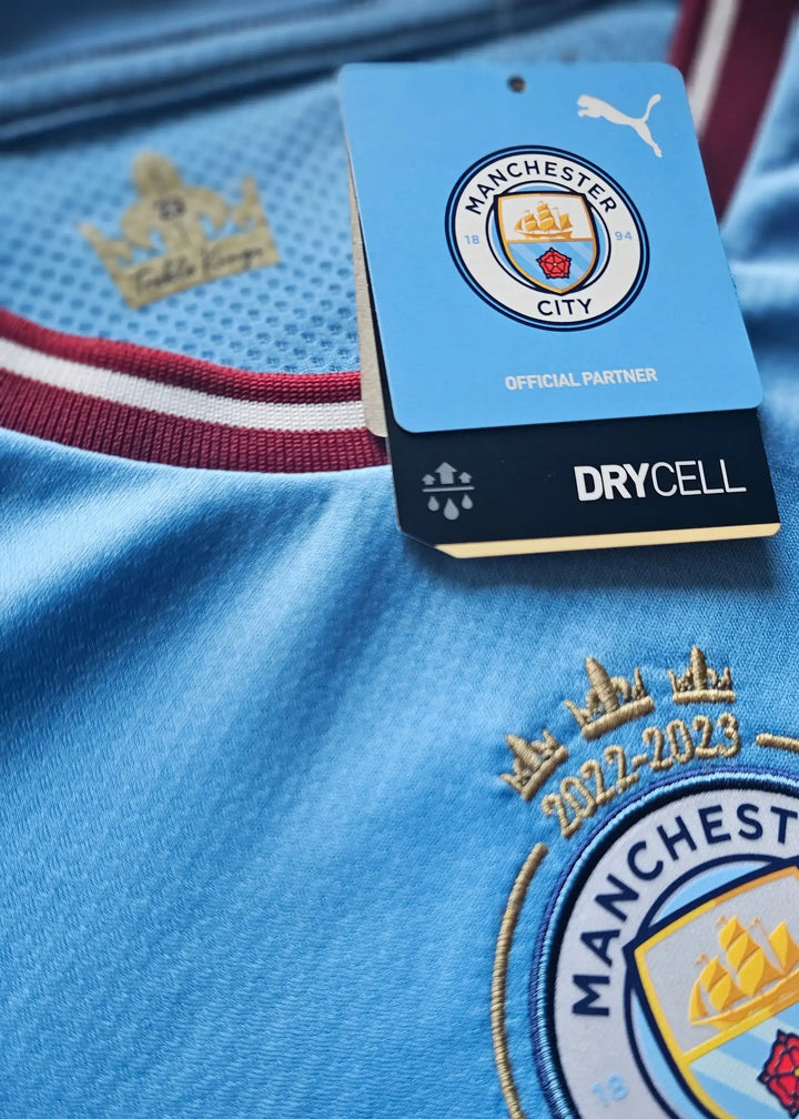 Crest detail showing Manchester City logo, three stars above, and '2022-23' embroidery.