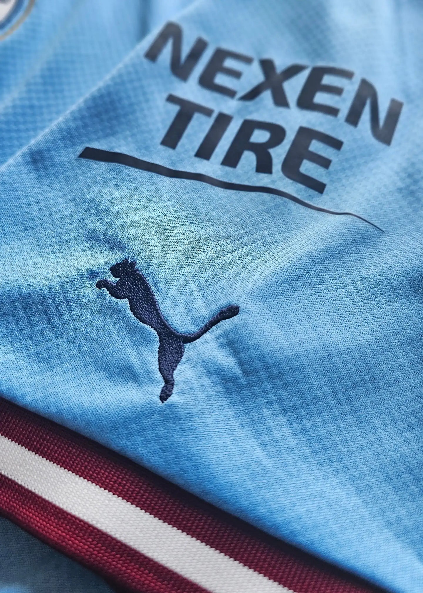 Detail showing Nexen Tire sponsor and Puma logo on a blue football shirt.