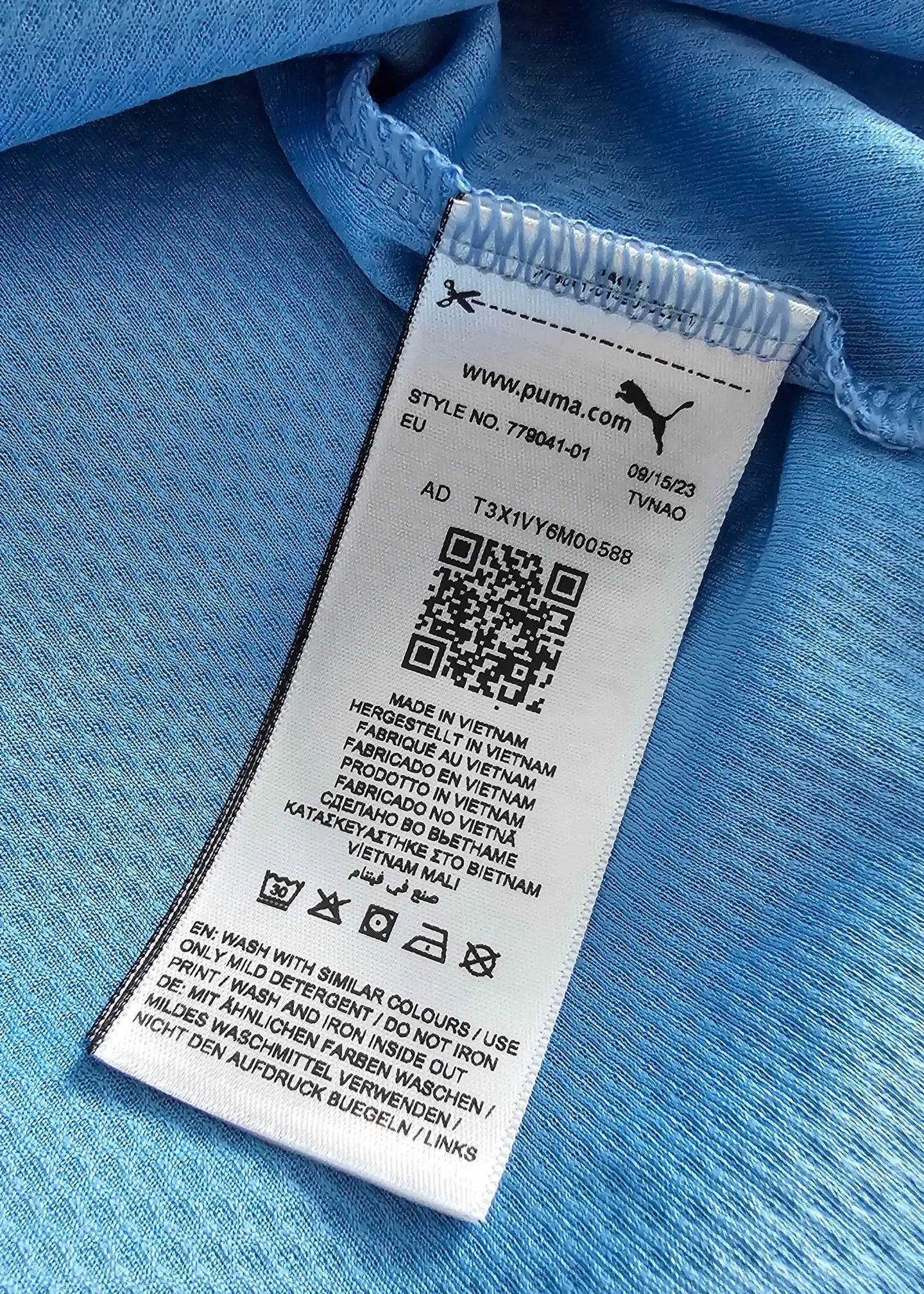 Care label showing washing instructions and style number, with light blue fabric background.