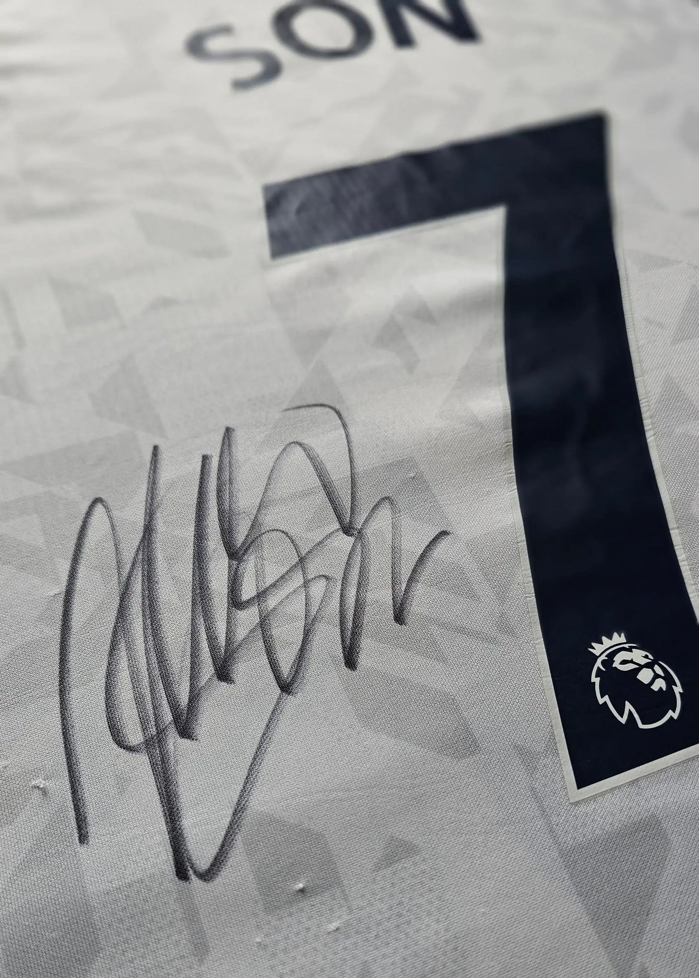Close-up of No. 7 and 'SON' with a visible signature on a white football shirt.