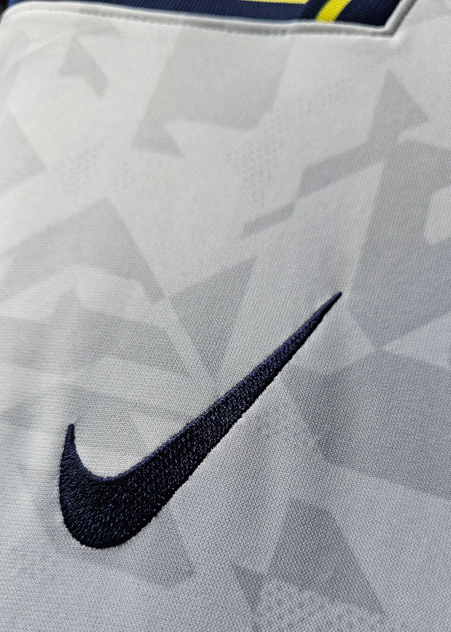 Close-up of the Nike swoosh logo on a white football shirt with a geometric pattern.